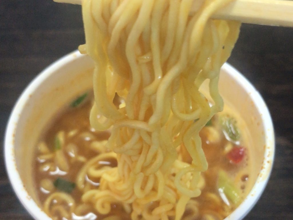 お箸でラーメンの麺を持ち上げている