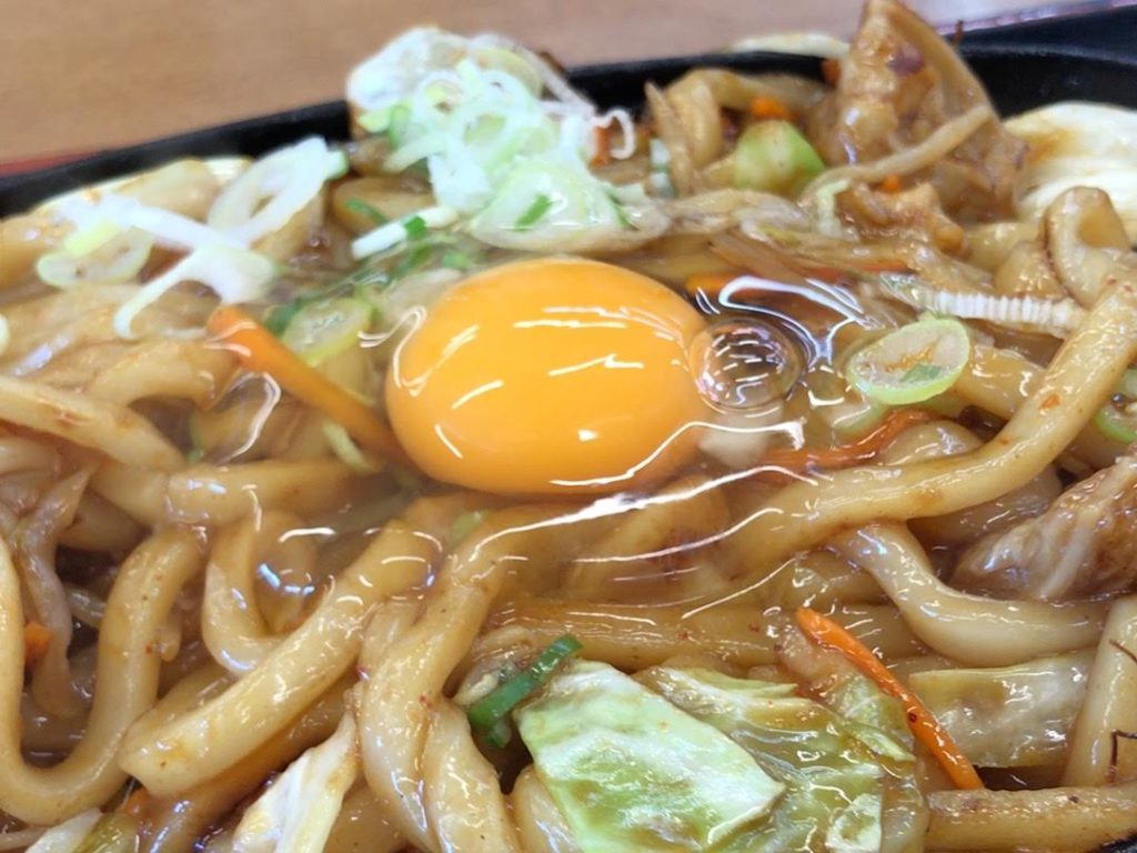 焼うどんに生たまごが乗っている