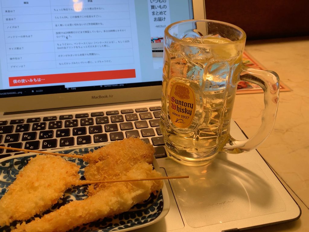 パソコンのキーボードの上に置かれたハイボールと串揚げ