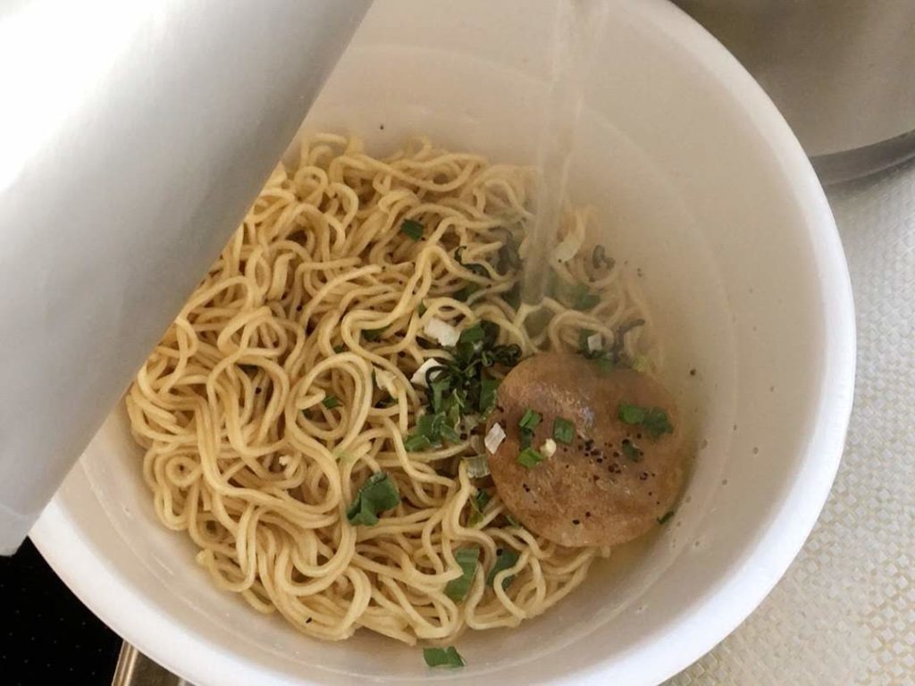 カップ麺にお湯を注いでいる