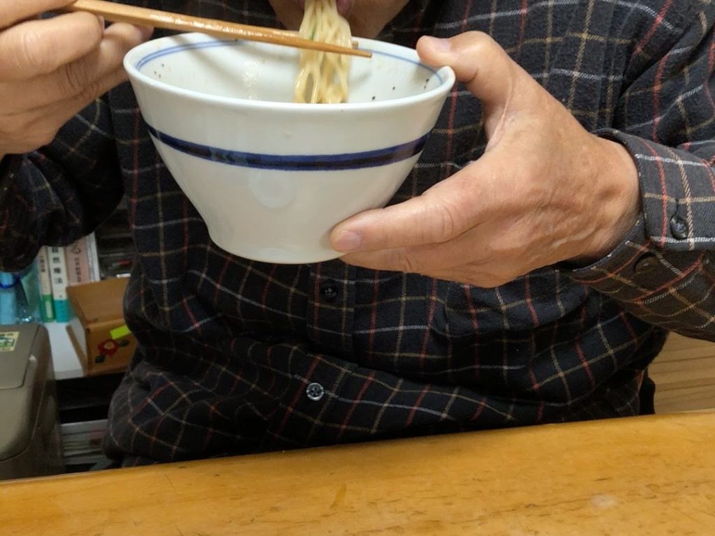 男性がラーメンを食べている