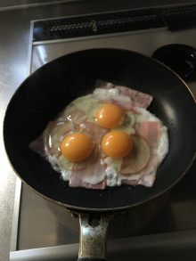 フライパンでベーコンと玉子を焼いている